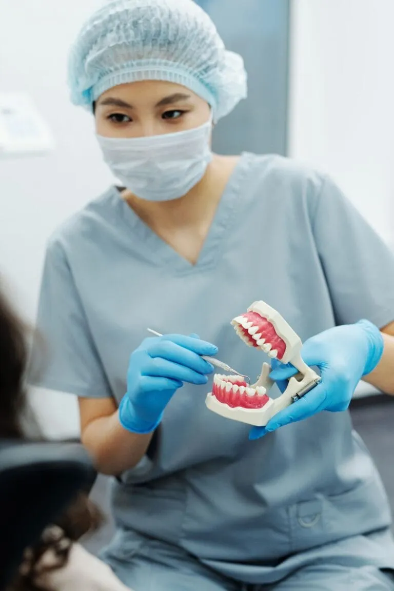 Stomatolog explicând unui pacient diferența dintre implant dentar și punte pe radiografie