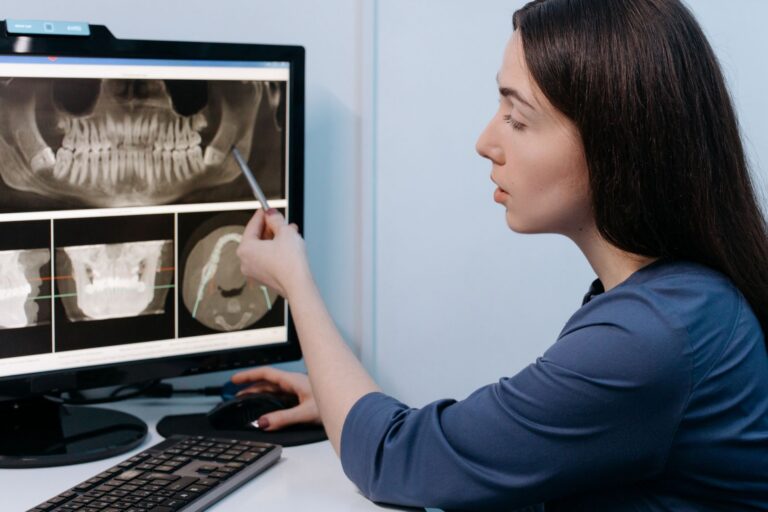 Medic stomatolog care analizează o radiografie dentară pe ecranul calculatorului din cabinet