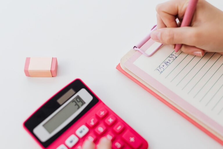 Calculator, agendă și model dentar pe un birou, simbolizând planificarea costurilor unui tratament